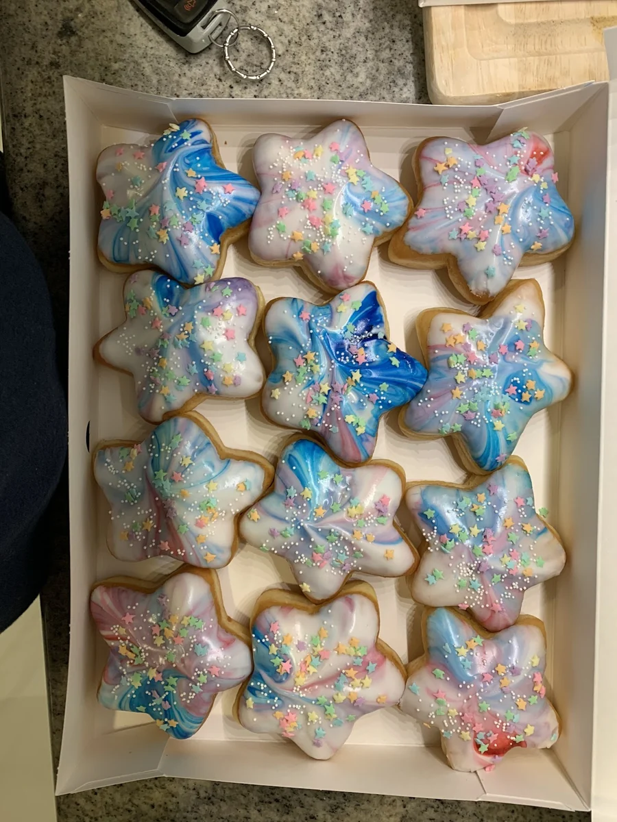 Custom star-shaped birthday donuts iced in blue, pink, and pastel with sprinkles